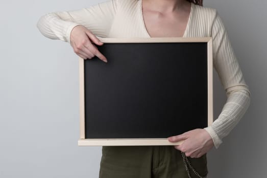 beautiful woman pointing on blank chalk blackboard on white background