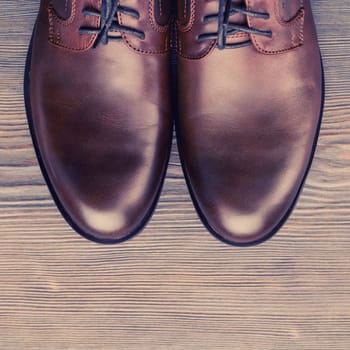 Fashionable men's classic brown shoes on a wooden background.