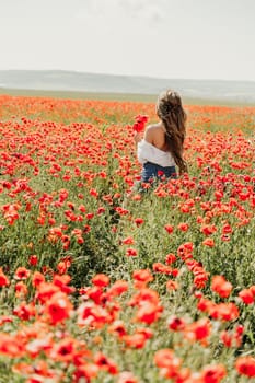 Woman poppies field. Back view of a happy woman with long hair in a poppy field and enjoying the beauty of nature in a warm summer day