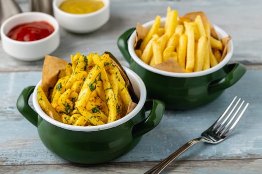 Golden French Fries in an enamel bowl with various sauces on the side