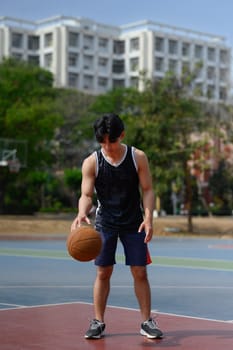 Full length portrait of sportsman playing basketball on court during a sunny day.