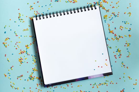 White open notebook on colorful background, festive, multicolored paper confetti