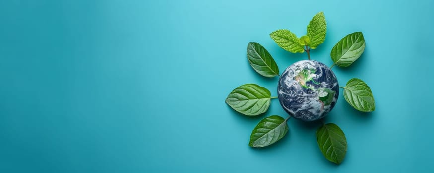 Earth planet surrounded by green leaves on blue background. Environmental conservation and sustainability concept.