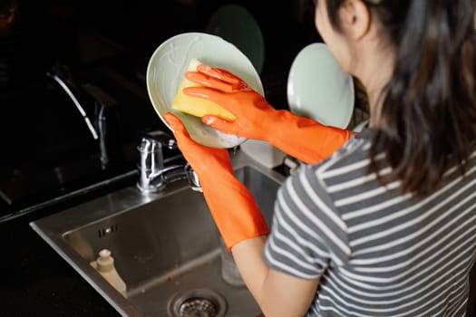 housewife cleans the house and washes the dishes at the sink. Cleaning home concept.