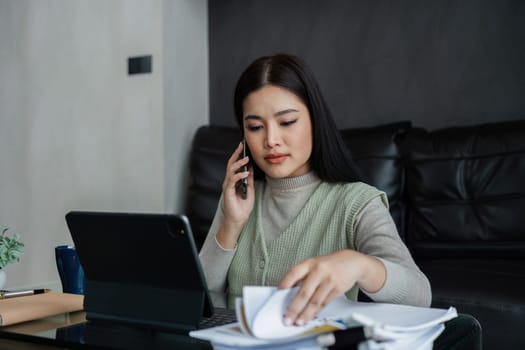 young asian business woman, freelance data accountant work from home, work remotely at home, talking with client on mobile .