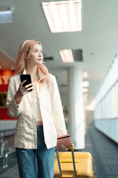 A woman asian walking in an airport. Mobile, suitcase and travel with a young female on an international trip for work or travel.