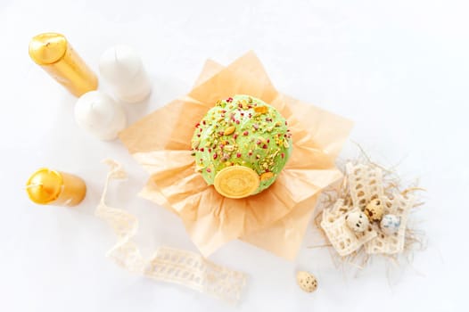 Traditional easter cake or sweet bread, quail eggs and green meringues in shape of nest over white background. Top view, close up. Easter treat, holiday symbol.