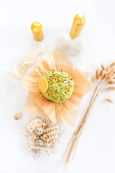 Traditional easter cake or sweet bread, quail eggs and green meringues in shape of nest over white background. Top view, close up. Easter treat, holiday symbol.