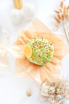 Traditional easter cake or sweet bread, quail eggs and green meringues in shape of nest over white background. Top view, close up. Easter treat, holiday symbol.