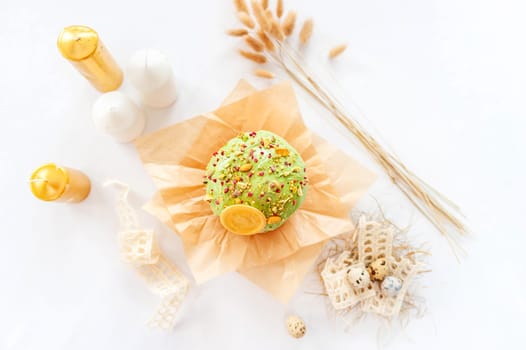 Traditional easter cake or sweet bread, quail eggs and green meringues in shape of nest over white background. Top view, close up. Easter treat, holiday symbol.