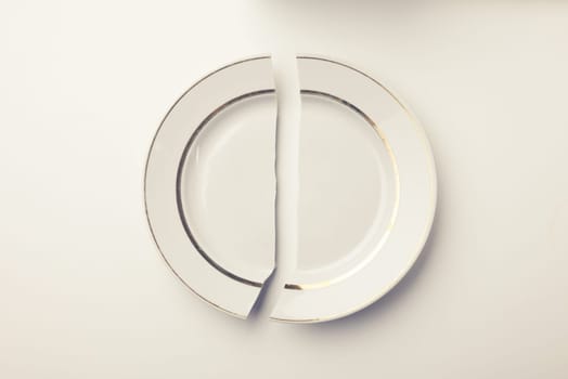broken white porcelain plate on a white background. concept lack of food