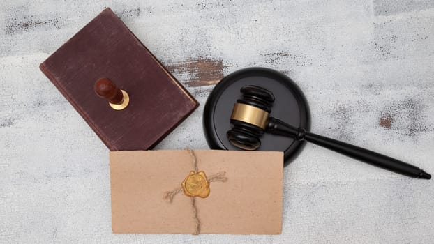 Judge's gavel, old book and parchment scroll with seal and stamp on an old wooden table. Law and justice concept