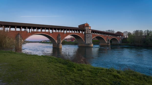 Beautiful view of Ponte Coperto (covered bridge) is a bridge over the Ticino river in Pavia at sunset, Lombardy, Pavia, Italy