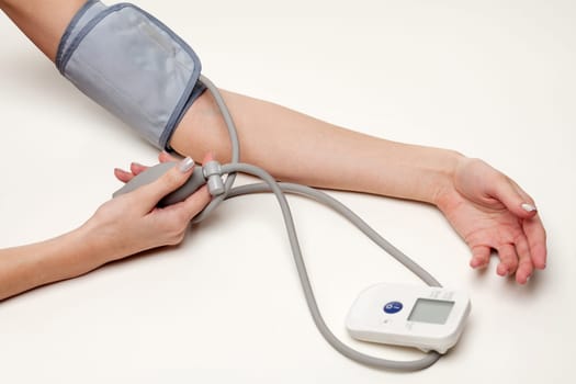 Blood pressure measurement. Woman hands with tonometer on white background.