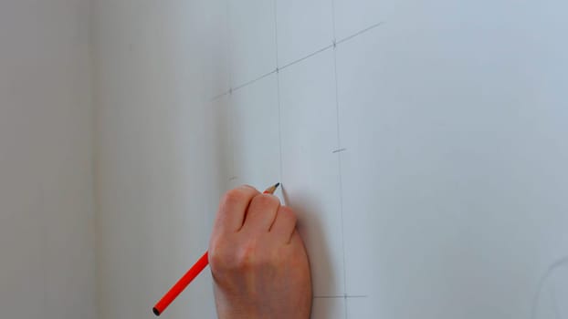 Builder draws marking on the wall. Worker making measurements.