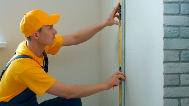 Engineer draws scheme on the wall. Builder making measurements on a white wall.