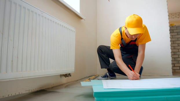 The worker draws a diagram on paper and on the walls. Repair in the house.