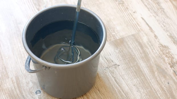 Bucket of water and a construction mixer. Builder knead glue for wallpapering.