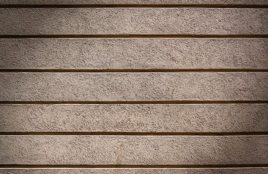 Beautiful exterior wall of a renovated house painted with a soft light color, enriched with a geometric horizontal striped texture. This design adds a contemporary and elegant touch 1