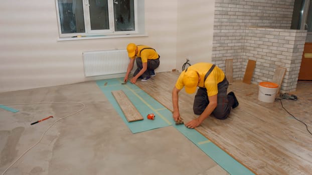 Brigade of workers laying laminate. Laying laminate.