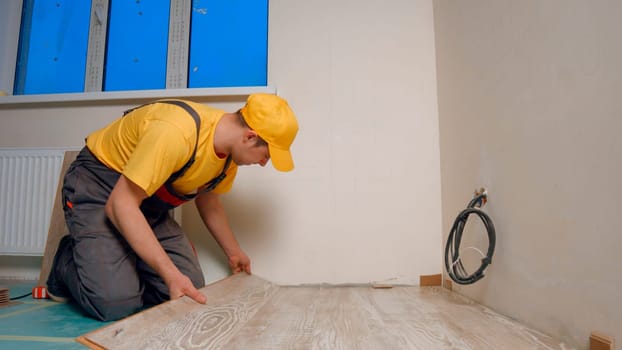 A worker is laying a new floor. Laying laminate in the house.