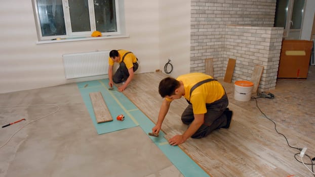 Workers lay the floor in the house. Laying laminate.