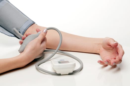 Blood pressure measurement. Woman hands with tonometer on white background.	