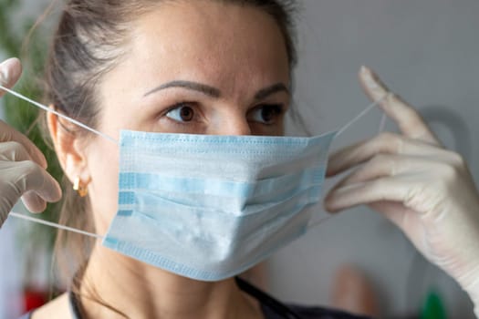 Shot of the nurse in the medical gloves holding medical mask