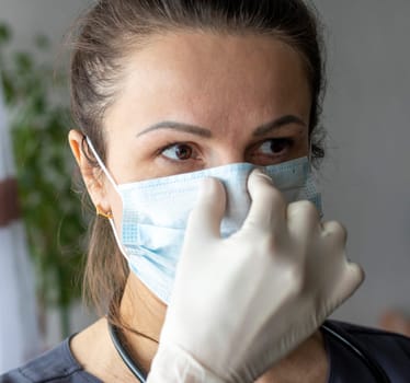 Shot of the nurse in the medical gloves holding medical mask
