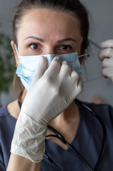 Shot of the nurse in the medical gloves holding medical mask