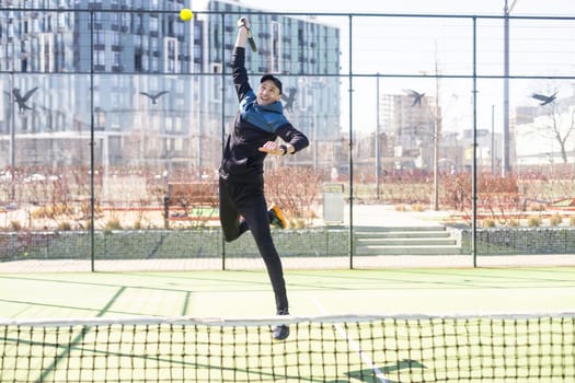Young padel player trains by catching high balls. High quality photo