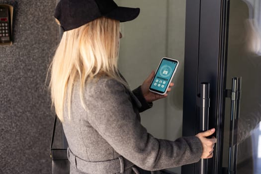 Woman locking smartlock on the entrance door using a smart phone. Concept of using smart electronic locks with keyless access. High quality photo