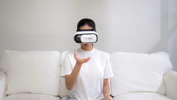 Young woman using virtual reality VR goggle at home for vivancy online shopping experience. The virtual reality VR innovation optimized for female digital entertainment lifestyle.