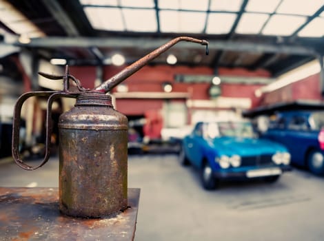 Grungy Rusty Can With A Drip Of OIl In An Automobile Repair Shop With Vintage Cars And Copy Space