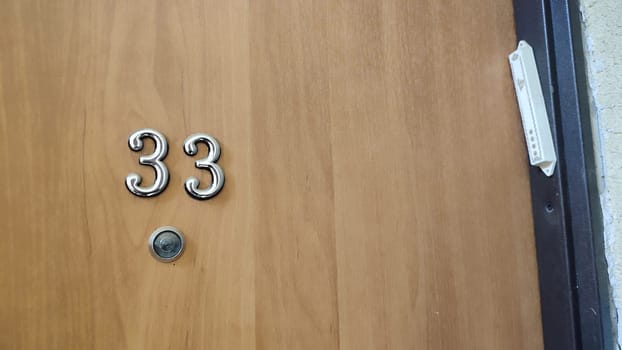numbers 33 on a white exterior apartment door, symbol objects, sky. High quality photo