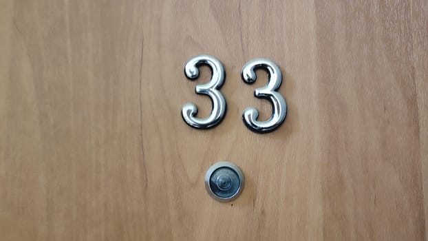 numbers 33 on a white exterior apartment door, symbol objects, sky. High quality photo
