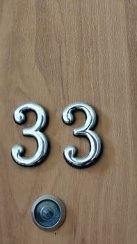 numbers 33 on a white exterior apartment door, symbol objects, sky. High quality photo