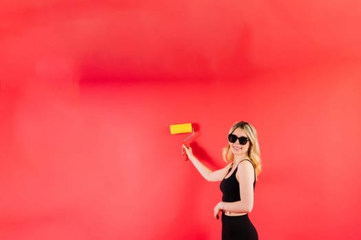 Young woman with roller brush on red white backgrounds Instruments accessories for renovation room