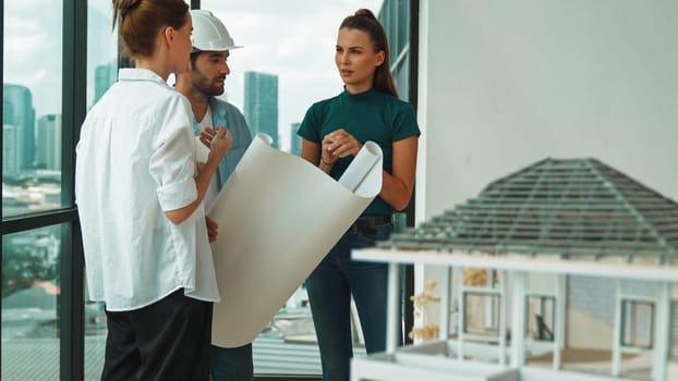 Professional architect engineer team talking, sharing, brainstorming about design while manager hold at project plan. Young architect holding plan while manager listen and point at plan. Tracery