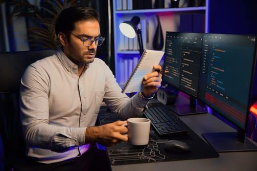 Smart IT developer working with coffee on software development coding on pc screen, reading note with newest application project program update online website data at neon light cyber office. Surmise.