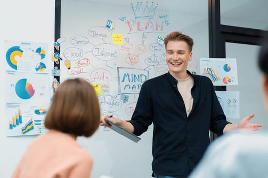 Professional male leader presents start up project by using mind map, colorful sticky notes and business statistic graph with confident while investor listening at business meeting. Immaculate.