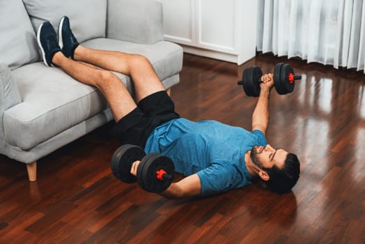 Athletic body and active sporty man using furniture for effective targeting muscle gain with weight lifting dumbbell exercise at gaiety home as concept of healthy fit body home workout lifestyle.