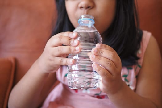 child drinking bottle of water .