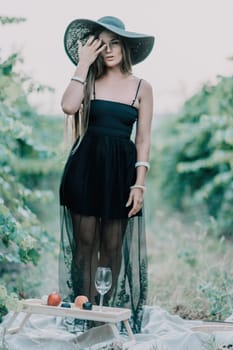 Woman at autumn winery. Portrait of happy woman holding glass of wine and enjoying in vineyard. Elegant young lady in hat toasting with wineglass smiling cheerfully enjoying her stay at vineyard