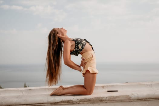 Woman park yoga. Side view of free calm bliss satisfied woman with long hair standing in morning park with yoga position against of sky by the sea. Healthy lifestyle outdoors in park, fitness concept