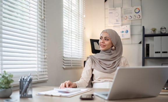 Attractive Muslim accounting business woman working using laptop in modern office.