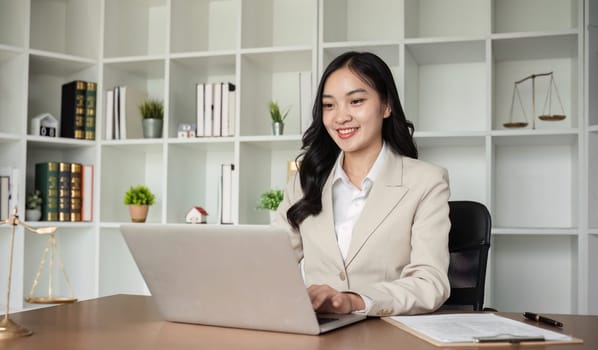 A female Asian lawyer reviews business and real estate laws. Legal consultants provide legal advice and guidance online via laptops in lawyers' offices..