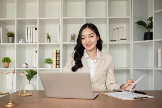 A female Asian lawyer reviews business and real estate laws. Legal consultants provide legal advice and guidance online via laptops in lawyers' offices..