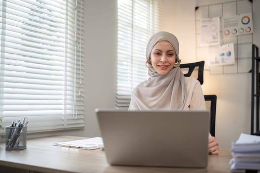 Attractive Muslim accounting business woman working using laptop in modern office.