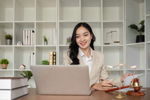 A female Asian lawyer reviews business and real estate laws. Legal consultants provide legal advice and guidance online via laptops in lawyers' offices..